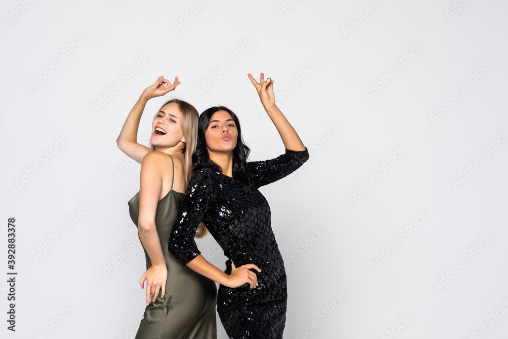 Two pretty young women showing peace sign wearing evining dressed makeup standing isolated over white background