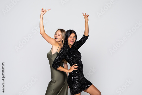 Φωτογραφία Portrait of two attractive happy women in sparkly dresses hugging and looking at
