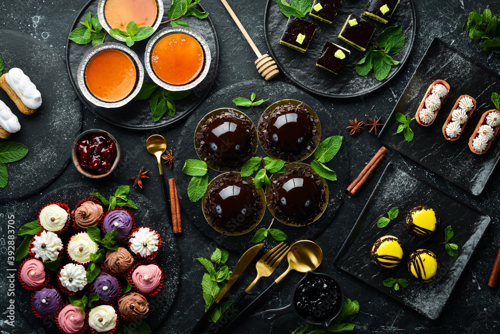 Set of sweets and desserts for coffee and tea on a black stone background. Top view. Rustic style. Set of sweets and desserts for coffee and tea on a black stone background. Top view. Rustic style.