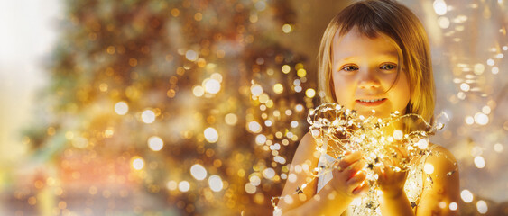 little girl with christmas lights looks at the camera