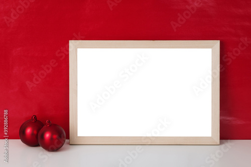 Blank wooden photo frame mockup template and christmas balls on red blackground.