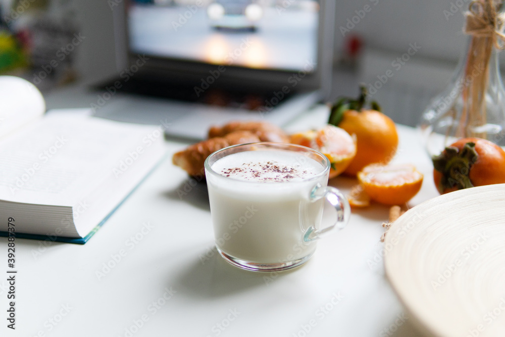Composition with New Year's assortments on a white table. Christmas mood. on a white background coffee croissant tangerines and Christmas red balls. Close-up in the foreground of a mug with milk. Composition with New Year's assortments on a white table. Christmas mood. on a white background coffee croissant tangerines and Christmas red balls. Close-up in the foreground of a mug with milk.