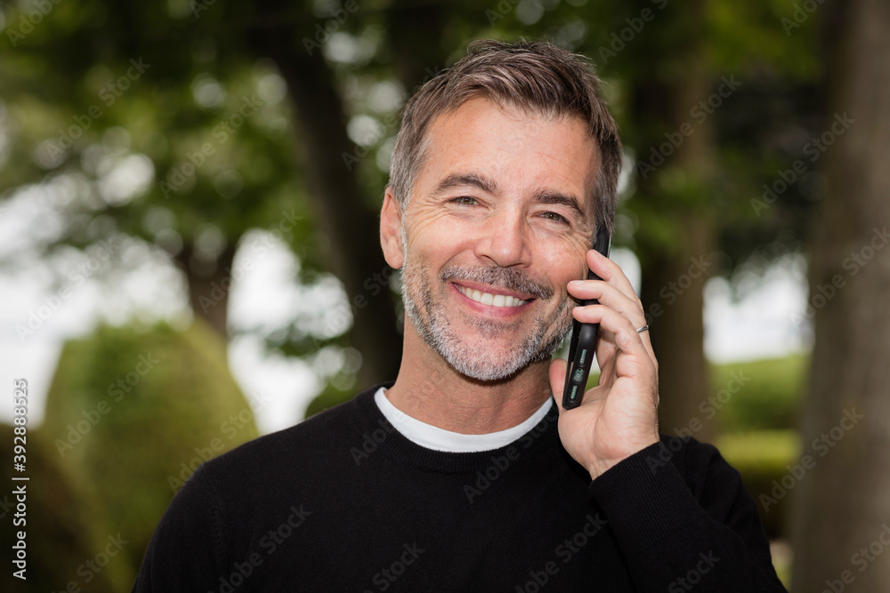 Handsome Mature Happy Man Smiling At The Camera. He is on a phone. Handsome Mature Happy Man Smiling At The Camera. He is on a phone.