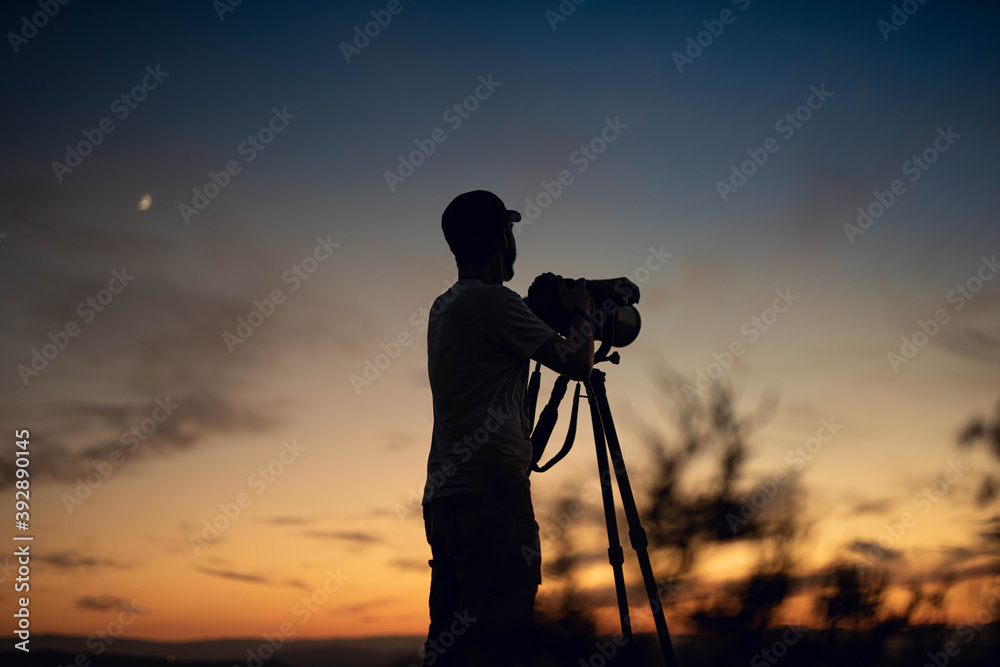 silhouette of nature photographer with super telephoto lens at sunset