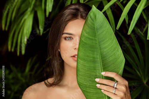 Beautiful brunette woman closeup with plants. Green, flower, emotion portrait natural beautiful big ey