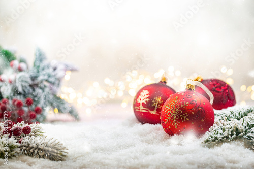 Christmas red decorations on snow with fir tree branches and christmas lights. Winter Decoration Background