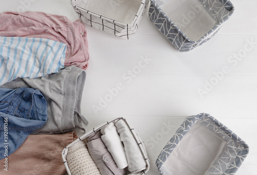 A group of organic cotton clothing set on a white table is ready to be folded into white baskets.The concept of closet organization. Colors in the Scandinavian style. Using the Komari method. photo