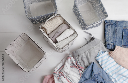 A group of organic cotton clothing set on a white table is ready to be folded into white baskets.The concept of closet organization. Colors in the Scandinavian style. Using the Komari method. photo