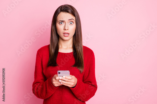 Photo of lovely young lady hold cellphone confused scared look camera wear red pullover isolated pink color background