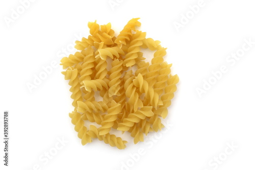 Spiral pasta lie in a heap on a white background
