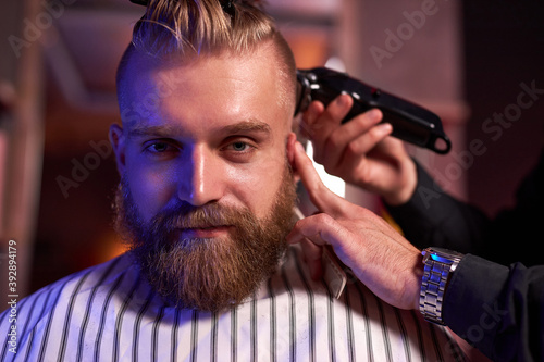 confident male hairstylist cut hair to elegant stylish man sitting in salon, young male enjoy the process of cutting