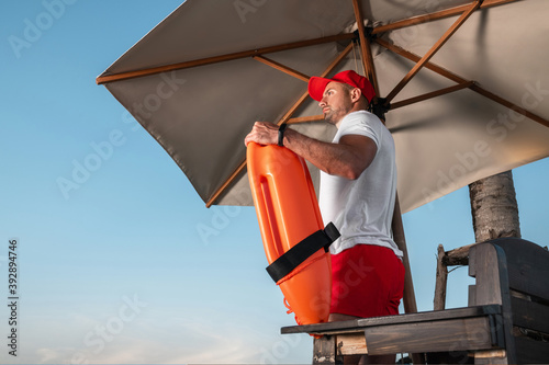 Tableau sur toile Portrait of a young lifeguard with a rescue orange buoy
