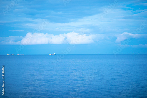 Calm blue sea with ships in the background.
