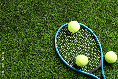 Tennis racket and balls on green grass, flat lay. Space for text © New Africa