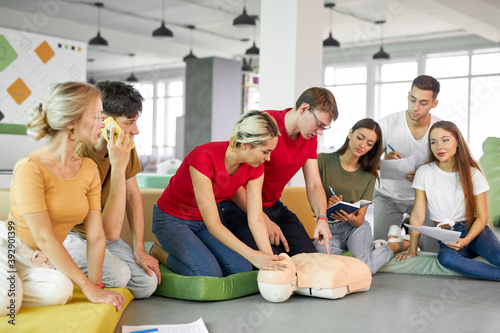 CPR class with young caucasian instructors speaking and demonstrating help first aid, cpr mannequin on the floor