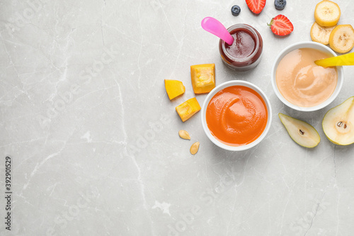 Healthy baby food and ingredients on grey table, flat lay. Space for text