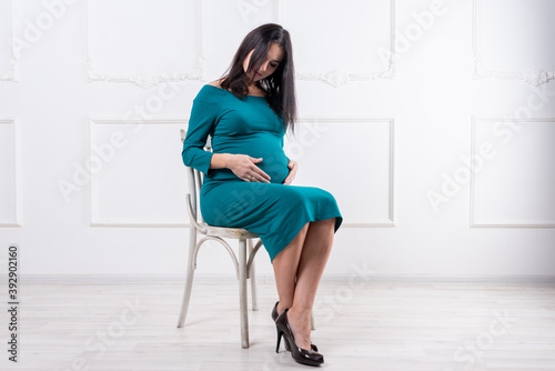 A pregnant girl is sitting on a chair.