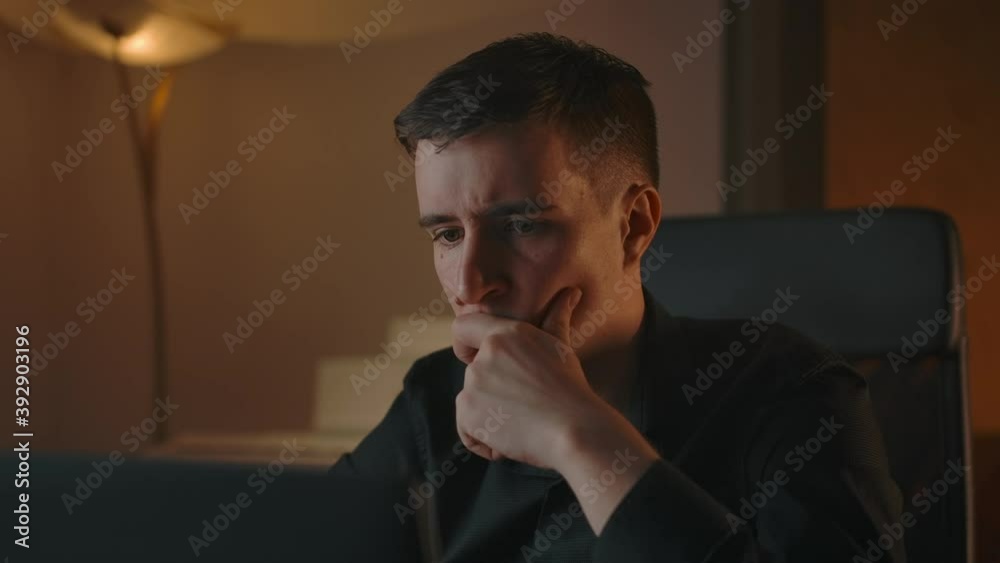 Close-up of thinking caucasian male indoor of night interior. Handsome man doubts in his important financial business decision, sitting at home behind laptop screen. Close-up of thinking caucasian male indoor of night interior. Handsome man doubts in his important financial business decision, sitting at home behind laptop screen.