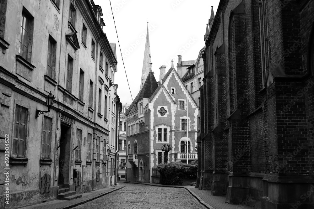 Fototapeta premium Dark mystical street of european city and gothic house, black and white photo