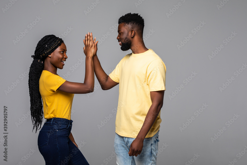Obraz premium Excited emotional young cute african couple posing give a high five to each other.