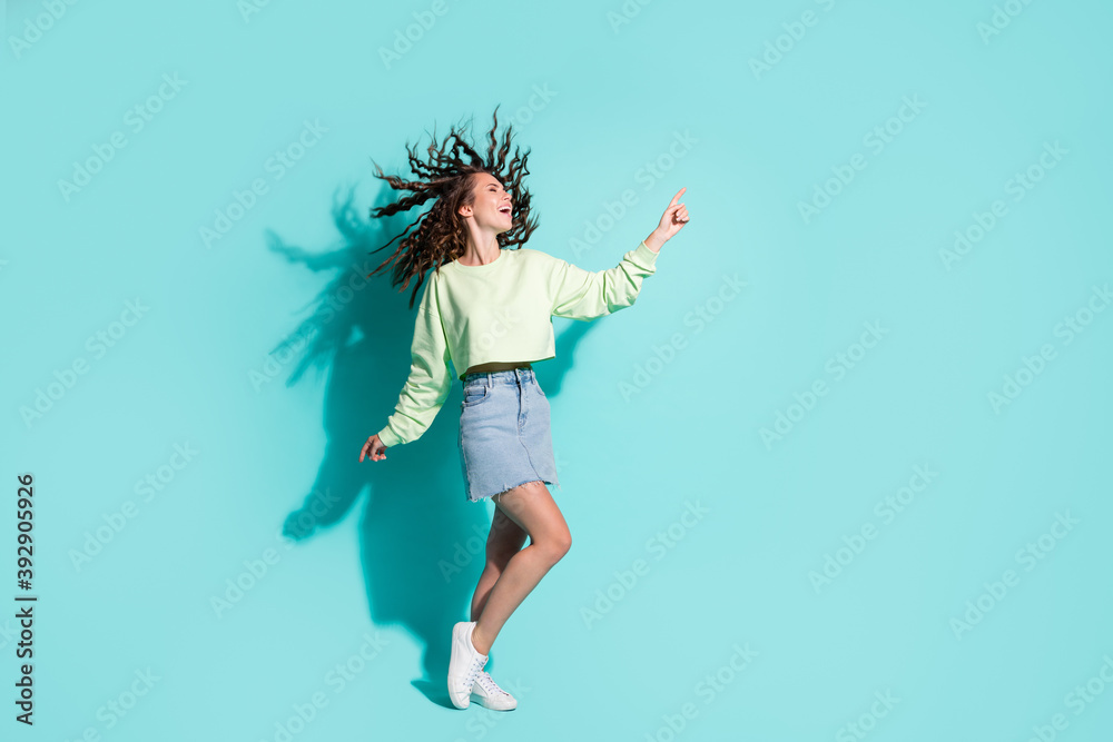 Full length body size photo of brunette girl dancing at party wearing denim skirt crop isolated on vibrant teal color background Full length body size photo of brunette girl dancing at party wearing denim skirt crop isolated on vibrant teal color background
