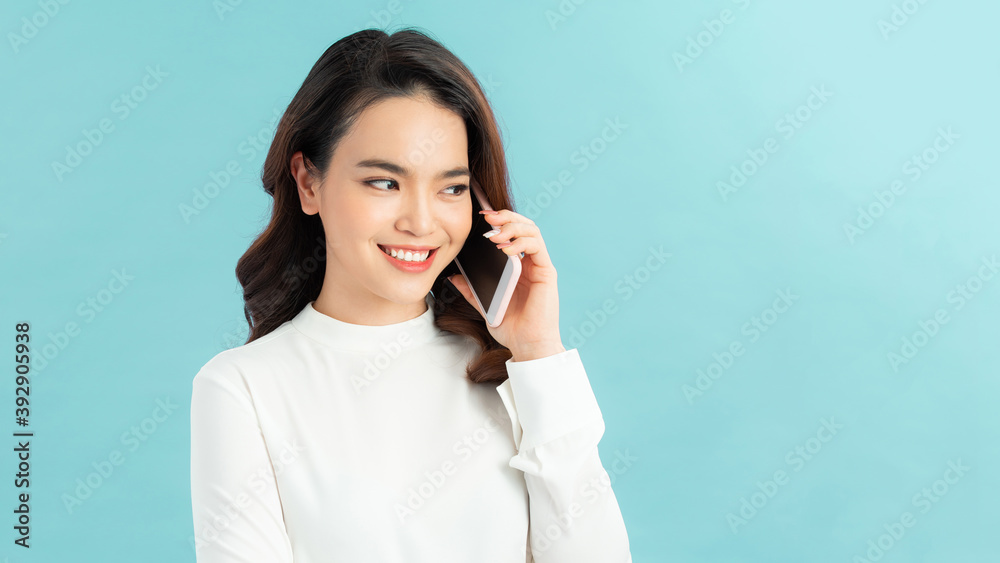 Smiling woman talking on the phone isolated on a blue background Smiling woman talking on the phone isolated on a blue background