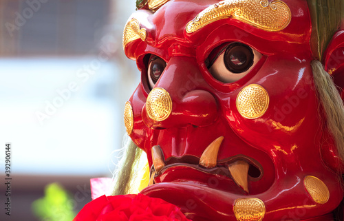 Low angle and close up face of traditional red Chinese god statue (Thousand-li Eye) with blurred outdoor background