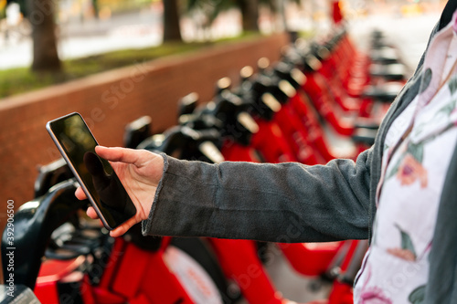 hand with phone next to a parking of bike rental