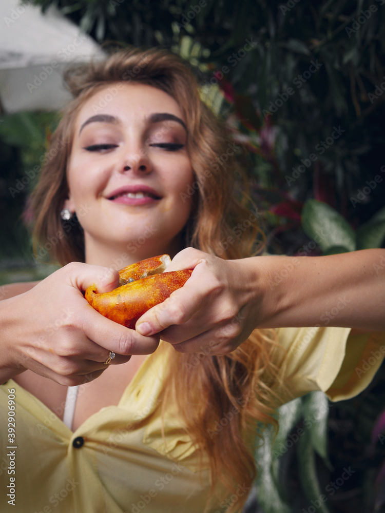 Young woman squeezes passion fruit in hand and passionately sucks its pulp