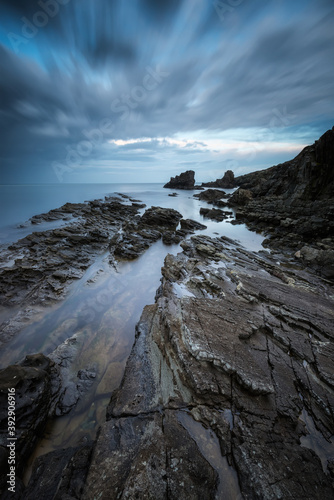 Amazing long exposure seascape with rocky beach at sunrise in the blue hour