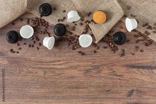 Espresso coffee capsules and roasted coffee beans on wooden background top view.