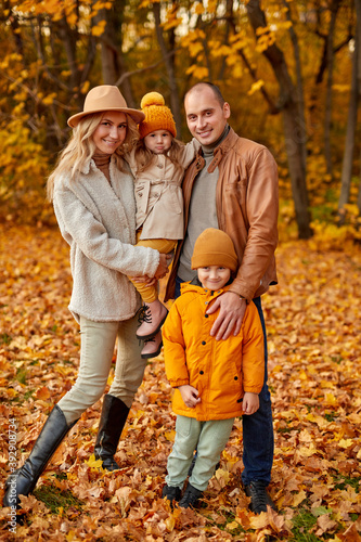 family in autumn park, on walk. caucasian parents with child relax, enjoy being in nature, posing together, wearing coats