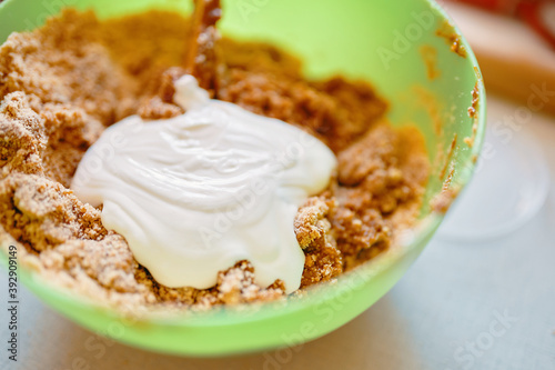 Mixing ingredients for cookies. Preparation of biscuits. Baking background. Dough with sour cream in a green bowl. Cooking classic cheesecake. © Konstantin Savusia