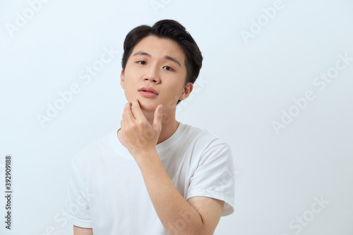 Handsome man. Charming young man keeping hand on chin and smiling while standing against white background