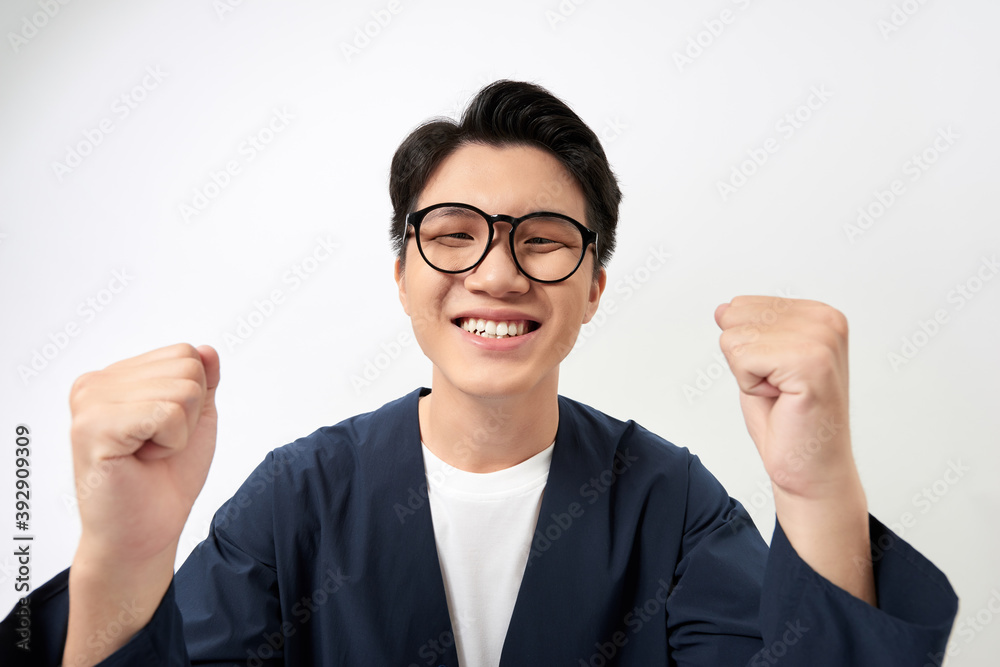 Excited happy young Asian man triumphing with raised hands. Excited happy young Asian man triumphing with raised hands.