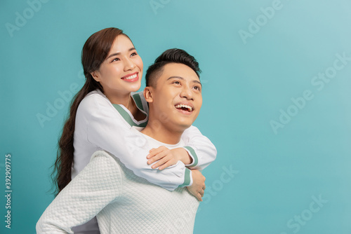 Happy man carrying his girlfriend on the back on blue background