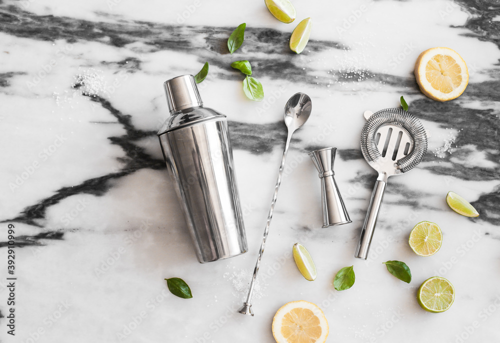 Cocktail set on the marble background - lemons, limes, shaker, spoon, ice Cocktail set on the marble background - lemons, limes, shaker, spoon, ice