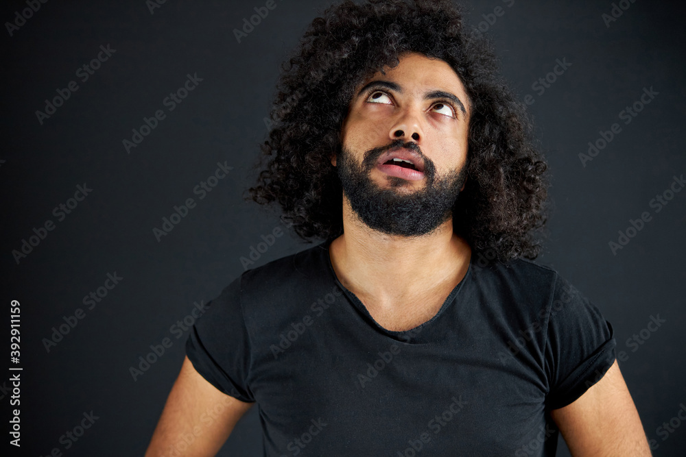 what are you talking about. curly male looking up, think. he is tired of listening to talks around, isolated black background what are you talking about. curly male looking up, think. he is tired of listening to talks around, isolated black background