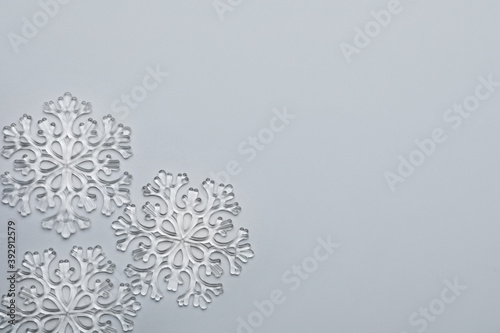 Beautiful decorative snowflakes on light grey background, flat lay. Space for text