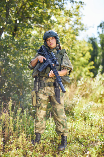 attractive brave military woman with a gun in forest, survival in wild forest, caucasian female in green suit camouflage suit with rifle or weapon