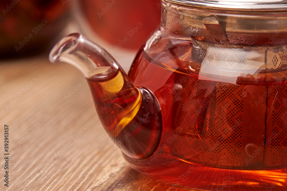 Close-up a hot tea in transparent glass teapot on the table with reflection. Close-up a hot tea in transparent glass teapot on the table with reflection.