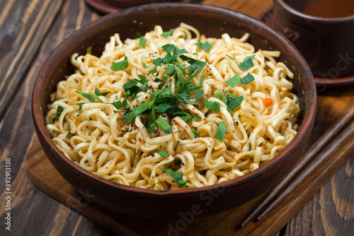 bowl with traditional Chinese noodles and tea on wooden background, closeup