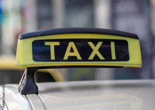 Taxi sign yellow color detail, defocused city street background