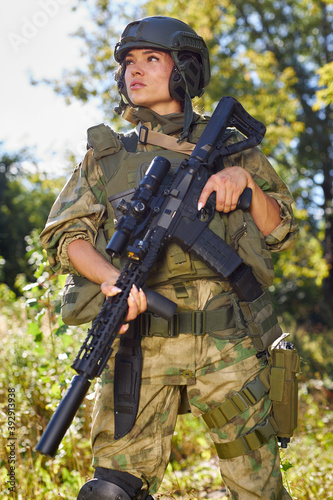 young caucasian military woman holds a gun in her hand in nature, she is going to hunt, hunting in forest is a hobby. game with weapons