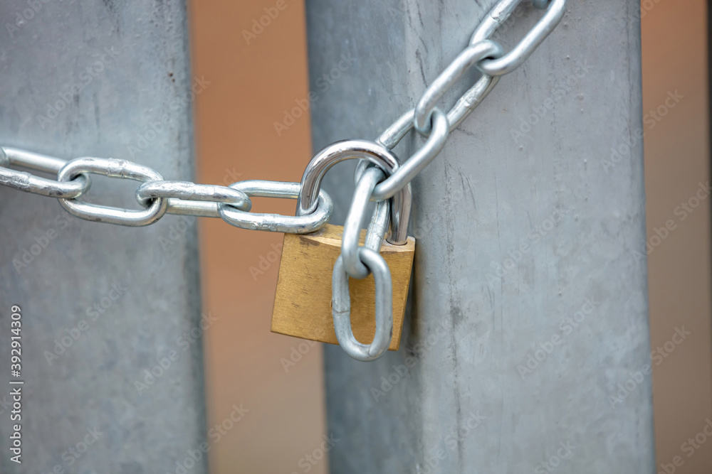 Heavy metal padlock with chain closeup on an entrance gate.