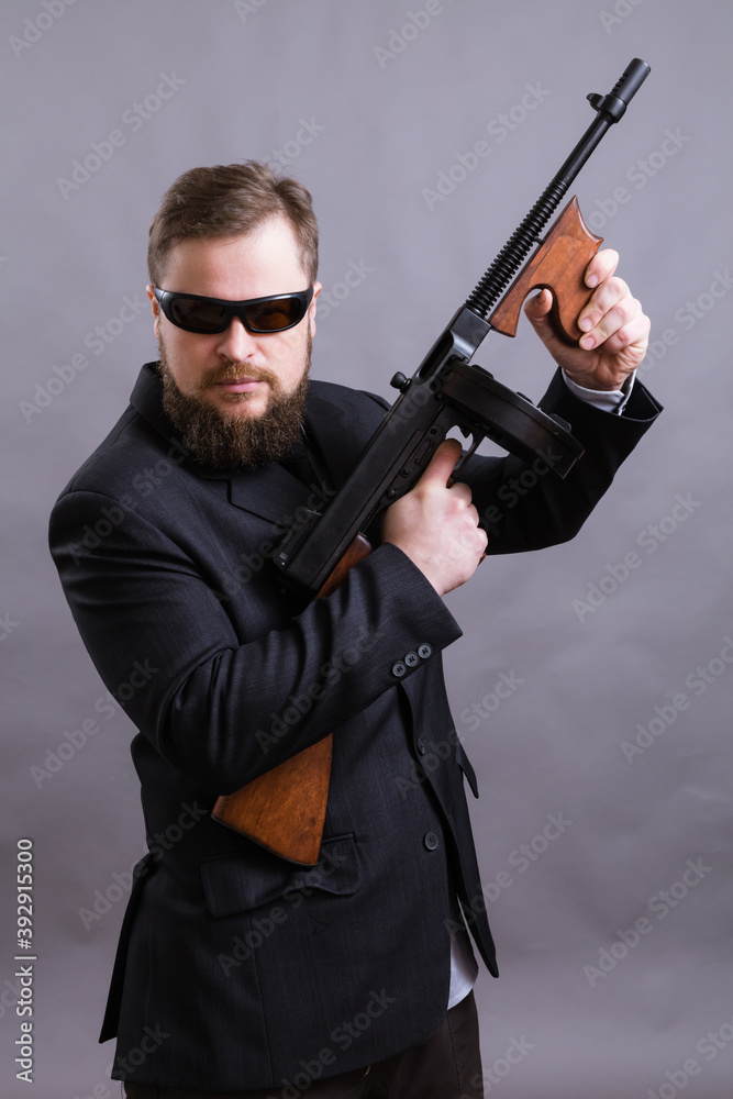 Mature man in sunglasses dressed in suit with tommy gun Mature man in sunglasses dressed in suit with tommy gun