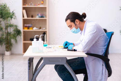 Young male chemist working in the lab during pandemic