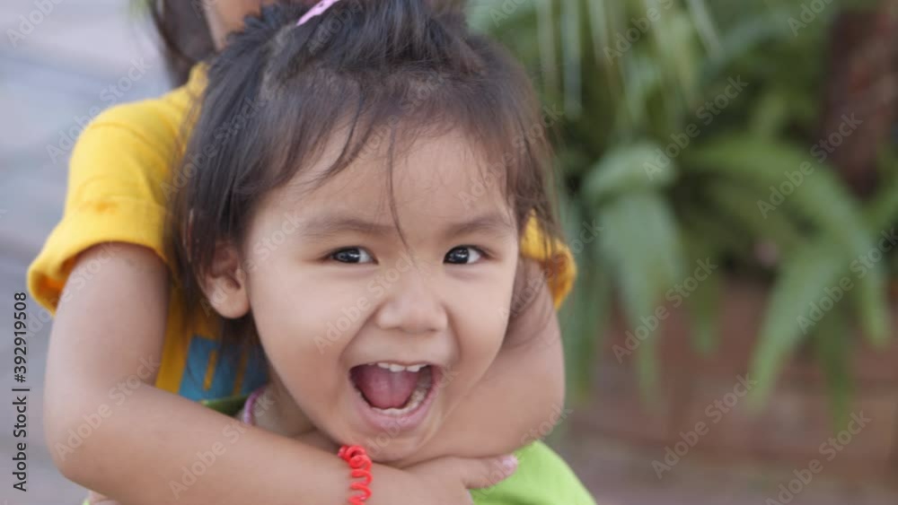 A three year old Asian girl playing with her sister in a cheerful, fun, cute In the park having fun. A three year old Asian girl playing with her sister in a cheerful, fun, cute In the park having fun.
