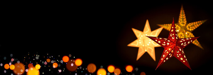Shining red and gold Christmas star lanterns framing a simple, extra wide black background as copy space