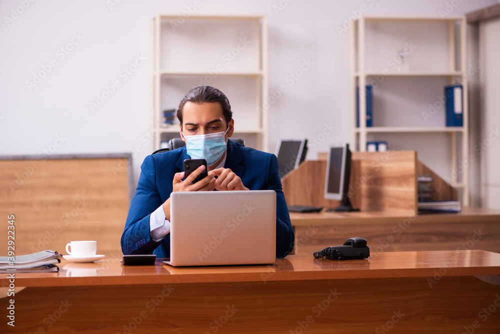 Young male employee working in the office wearing mask Young male employee working in the office wearing mask